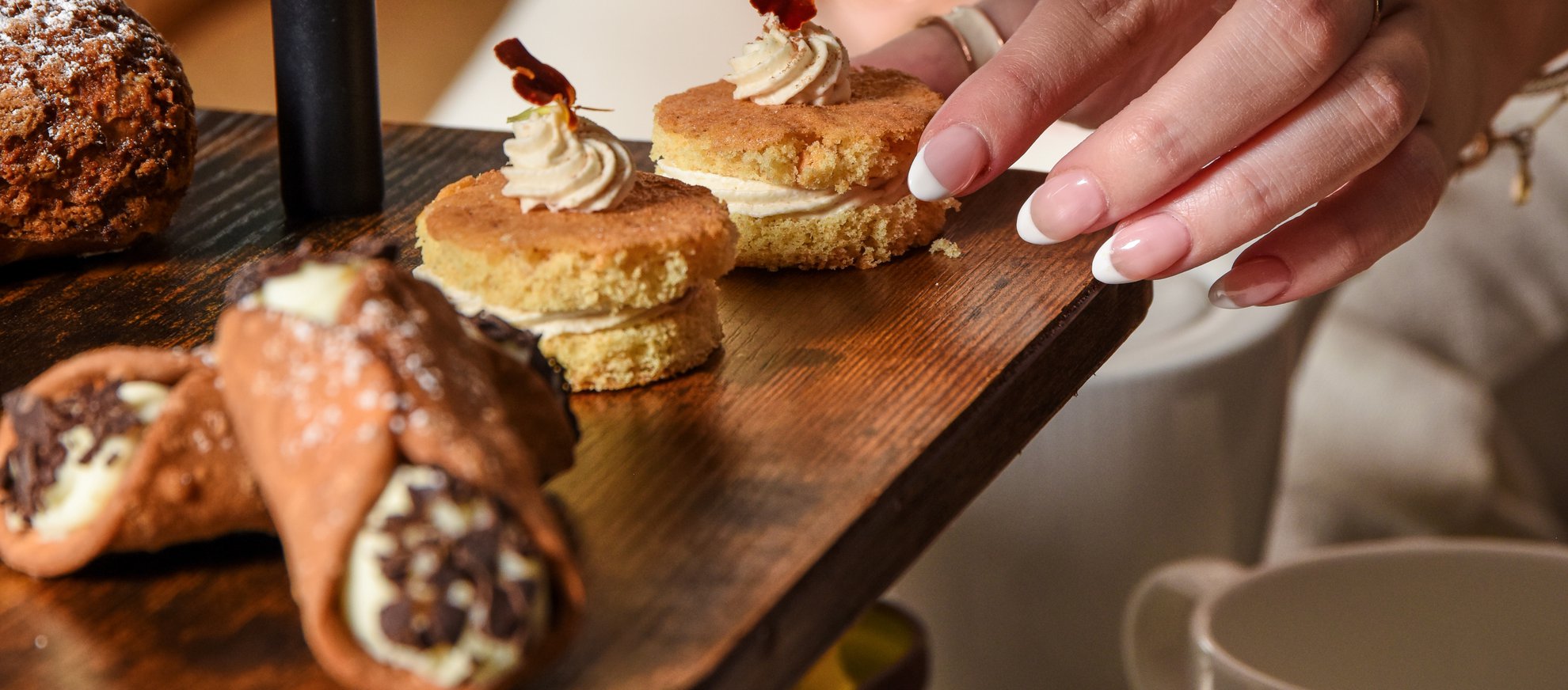 Fora afternoon tea tower woman reaching for seasonal tea cake brown butter and apple ganache 9.25 (2)